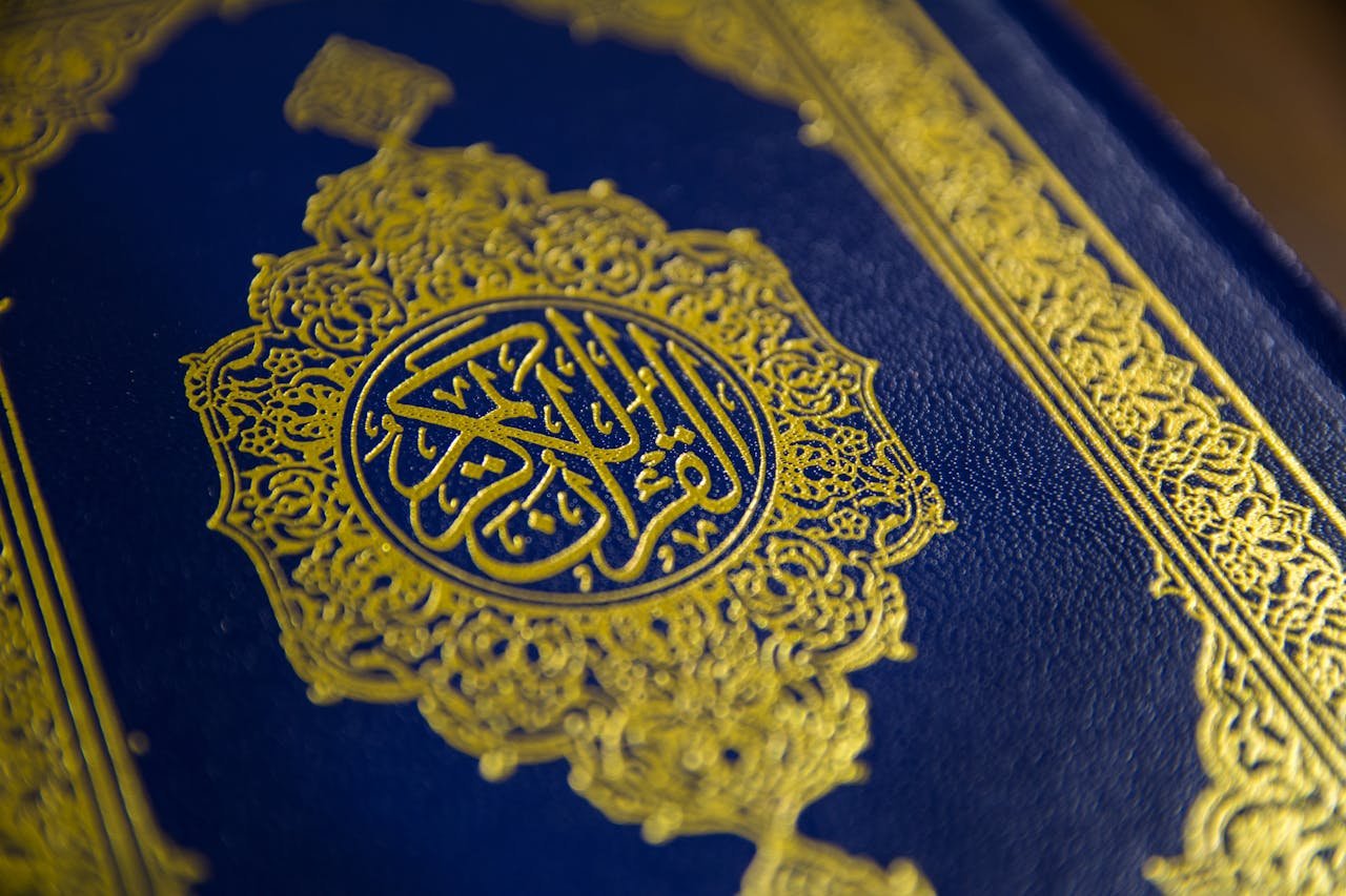 Elegant close-up view of the Quran's gold-embossed Arabic calligraphy on a blue cover.